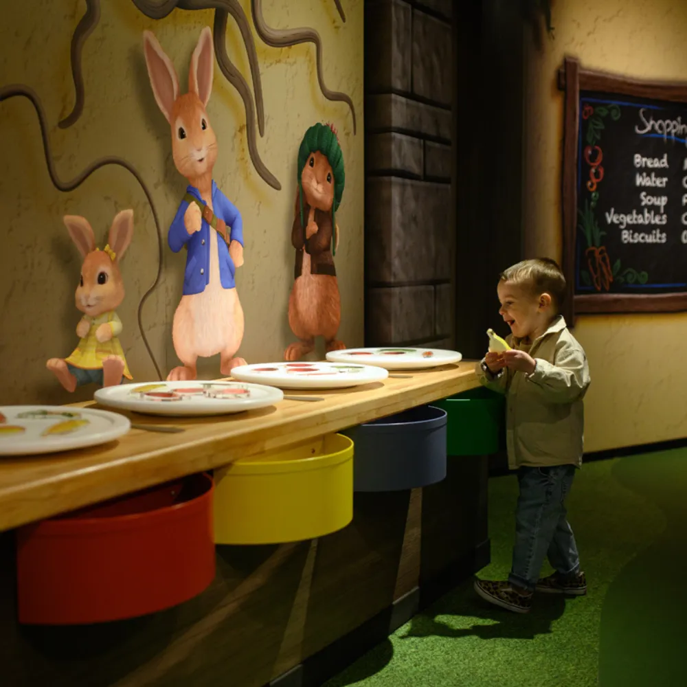 Toddler in The Burrow Dinner playing with dinner plates game
